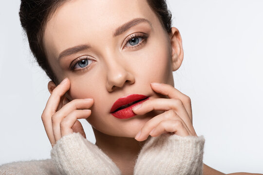 Portrait of young model with red lips touching face and looking at camera isolated on white.