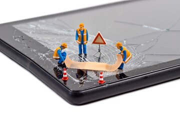 A team of miniature workmen repairing a broken mobile phone tablet touchscreen with a first aid...
