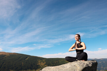 Fototapeta na wymiar Young woman practicing outdoor yoga in mountains, space for text. Fitness lifestyle