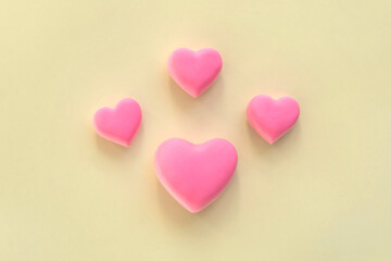 Fototapeta premium Pink hearts creative arrangement. Concept of love, romantic relationship symbol. 3d heart shape, on yellow background. Celebration of Valentine's Day or wedding.