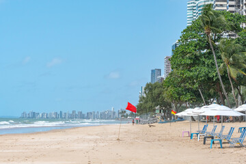 Beautiful beach with a red flag signaling danger in the water. Beach of Boa Viagem, Recife, PE, Brazil.