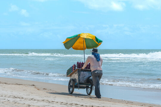 Street vendor pushing his cart on the sand of a beach in northeastern Brazil.