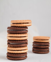 Stack of milk and chocolate cookies with cream filling close up on a white table.