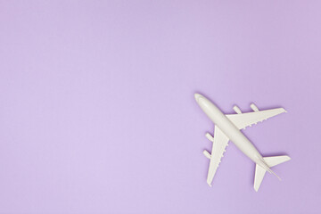 Airplane model. White plane on purple background. Travel vacation concept. Summer background. Flat lay, top view, copy space.