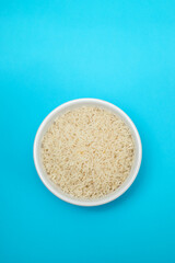 raw rice on white small bowl on blue