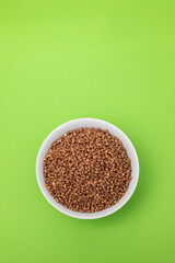 uncooked buckwheat in small white bowl on green