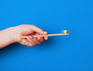 bamboo toothbrush in hand over blue background