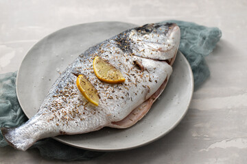 raw dorada with lemon on the plate on ceramic
