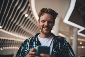 Guy using smartphone and drinking tea in office