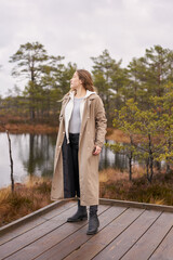 Lifestyle photo A girl trench coat in nature.  viru bog trail in Estonia. Travel,  exploration, healthy lifestyle, active rest