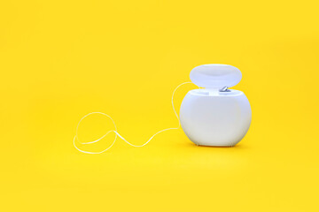 Dental floss for cleaning teeth on a yellow background. The concept of oral care and caries prevention. Dental care products and oral hygiene. Free space for text