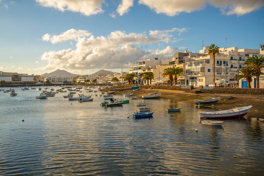 View of boats on beach in Baha de Arrecife Marina surrounded by shops, bars and restaurants at sunset, Arrecife, Lanzarote, Canary Islands