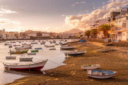 View of boats on beach in Baha de Arrecife Marina surrounded by shops, bars and restaurants at sunset, Arrecife, Lanzarote, Canary Islands