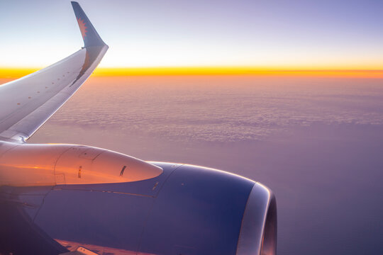 View of airplane engine and clouds over the sea at sunset Ocean