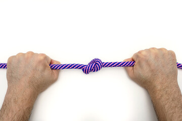 Male hands firmly hold a rope with a knot on a white background close-up. The concept of willpower...