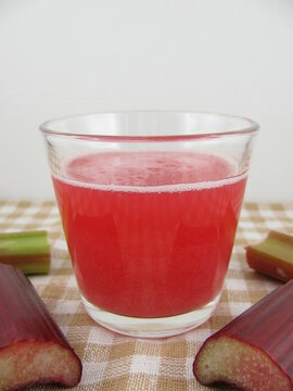Fresh rhubarb juice and pieces of a rhubarb stick