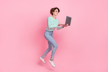 Full body profile photo of cute young bob hairdo lady run with laptop wear shirt jeans sneakers isolated on pink background