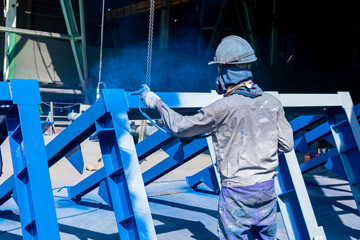 The painter uses a spray gun to paint a steel structure before transportation to the assembly yard.