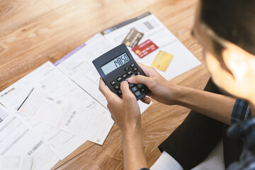 Top view financial owe asian young man sitting suffer, stressed and confused by calculate expense from invoice, credit card bill no money to pay mortgage or loan. Debt, bankrupt or bankrupt people.