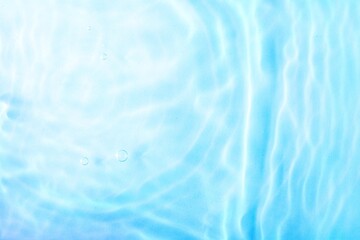 Transparent blue colored clear water surface texture with ripples, splashes and bubbles. Abstract background