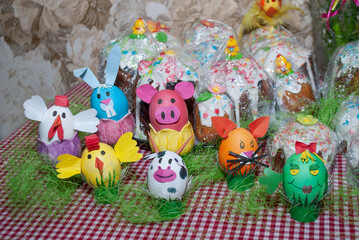 Bright colorful Easter eggs and rabbit ears, animals and Easter background with green moss. At home on a table against the background of a tablecloth in a cage