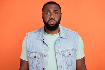 Photo of abused african guy dressed jeans waistcoat bloated cheeks isolated orange color background