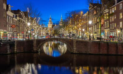 Obraz premium Beautiful old houses on the city waterfront of Amsterdam at sunset.
