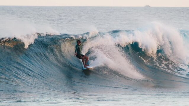 Surfer rides the wave in Maldives during sunset and falls