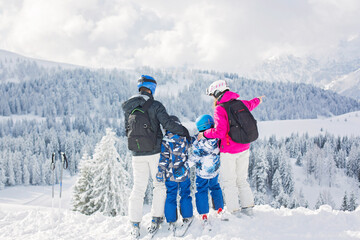 Fototapeta na wymiar Happy family, mother, father and two children, skiing