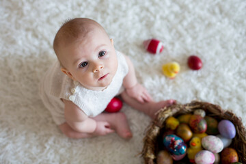 Cute little toddler baby boy, playing with colorful easter eggs and little decorative ducks,...