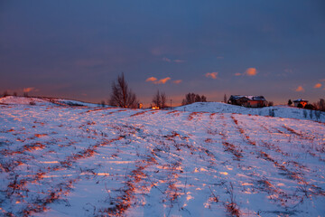 winter landscape: snow and ice in field, pink colorful sunset
