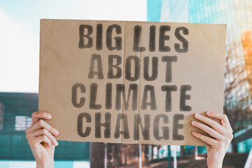 The phrase " Big lies about climate change " on a banner in men's hand with blurred sea on the background. Propaganda. Harvesting. Politic. Planet. Political. Strike. Strategy. Recycling . Strike