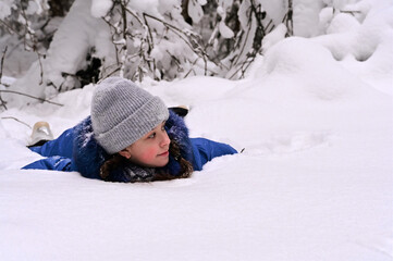 Fototapeta na wymiar pretty girl is lying in a snowdrift, resting. Outdoor activities in winter