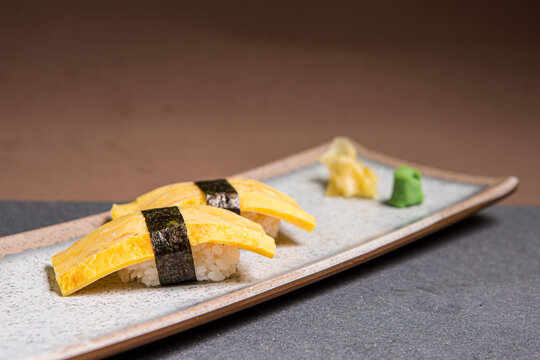 Tamagoyaki Sushi, sweet omelette wrap or Tamagoyaki, Japanese Omelette in a wooden plate. Front view with copy space.