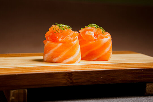 Salmon sushi freshly prepared. Japanese food, sushi roll of salmon in a wooden background. Fish and crustaceans slices. Front view with Copy Space.