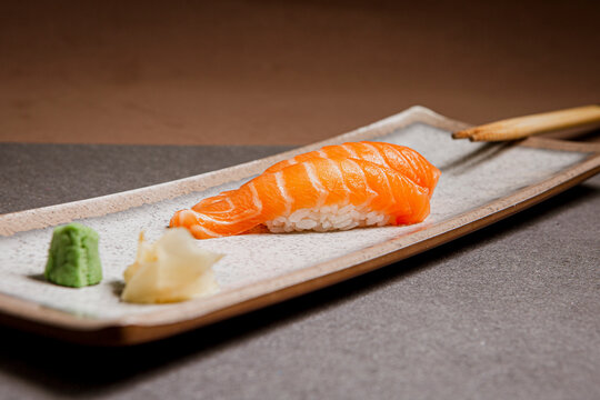 Salmon sushi freshly prepared. Japanese food, sushi roll of salmon in a wooden background. Fish and crustaceans slices. Front view with Copy Space.
