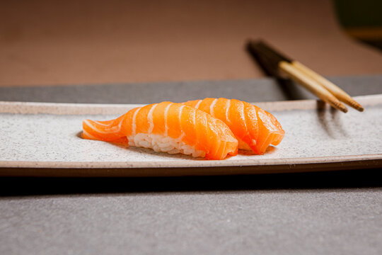 Salmon sushi freshly prepared. Japanese food, sushi roll of salmon in a wooden background. Fish and crustaceans slices. Front view with Copy Space.