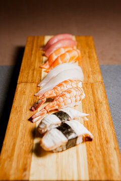 
Set of Sushi freshly prepared. Japanese food, sushi roll of shrimp in a wooden background. Fish and crustaceans slices. Front view with Copy Space.
