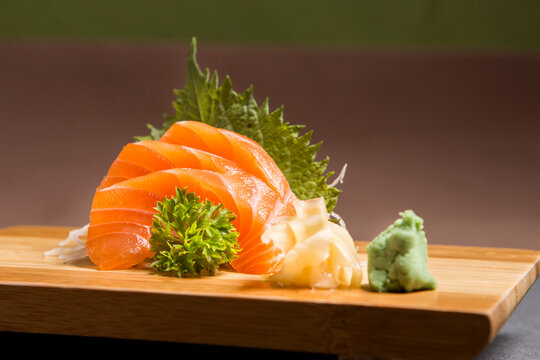 Sashimi japanese food, pieces of tuna, salmon in a wooden background. Fish slices. Front view with Copy Space.
