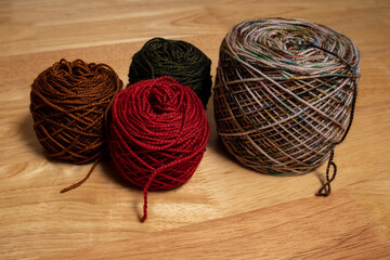 Multiple skeins balls of yarn with loose thread on wood table