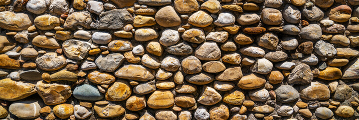 Vintage stone wall. Old castle wall texture as a background or texture. Decorative uneven cracked real stone wall surface.