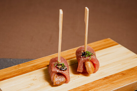Front View of freshly prepared especial Sushi Roll with Salmon and Tuna on Top of wooden plate / Japanese Food. Copy space.