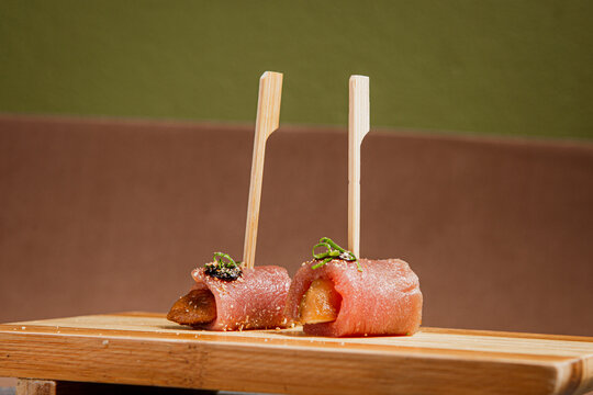 Front View of freshly prepared especial Sushi Roll with Salmon and Tuna on Top of wooden plate / Japanese Food. Copy space.
