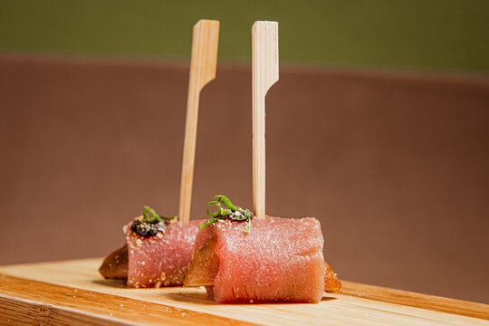Front View of freshly prepared especial Sushi Roll with Salmon and Tuna on Top of wooden plate / Japanese Food. Copy space.