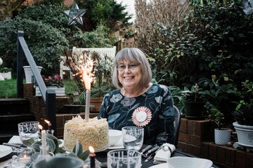 woman sat with a happy birthday badge and cake with sparklers