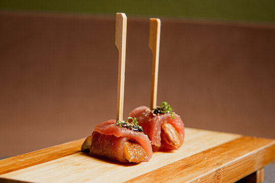 Front View of freshly prepared especial Sushi Roll with Salmon and Tuna on Top of wooden plate / Japanese Food. Copy space.
