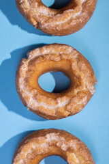Row of glazed cake donuts on a pastel background