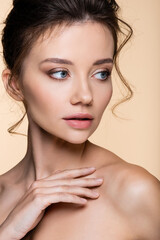 Naklejka premium Portrait of pretty woman with naked shoulders looking away isolated on beige.