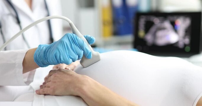 Doctor making ultrasound of fetus to pregnant woman patient in clinic closeup 4k movie slow motion