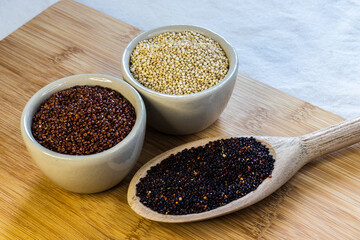 Red, black and white quinoa seeds on wooden background. Vegetarian food